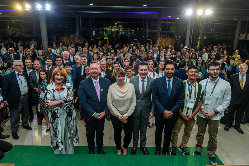 ICLEI leaders stand on the stage with attendees behind them at the opening ceremony of the ICLEI World Congress