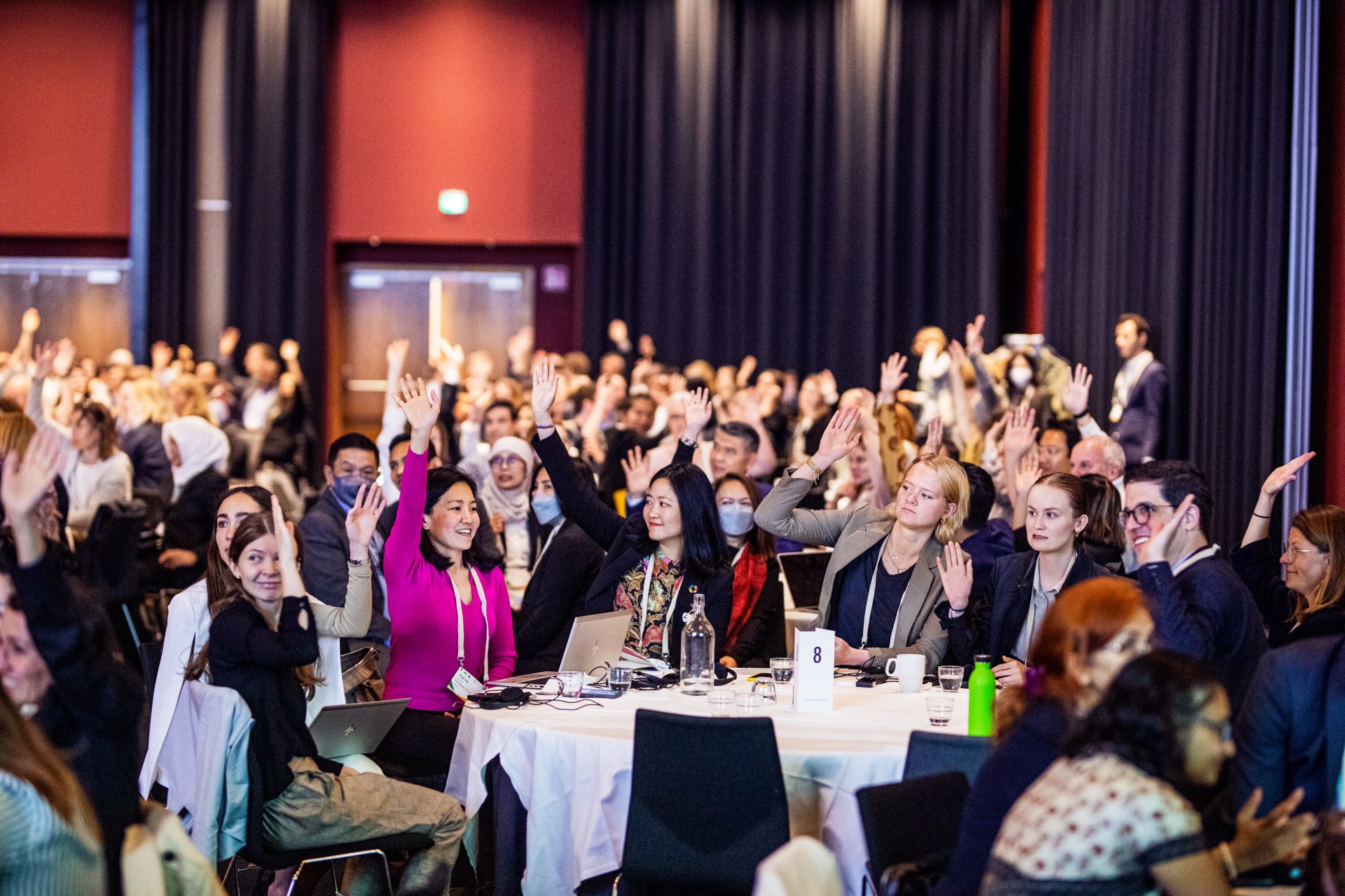 A group of attendees in the audience with their hands raised at the ICLEI World Congress.