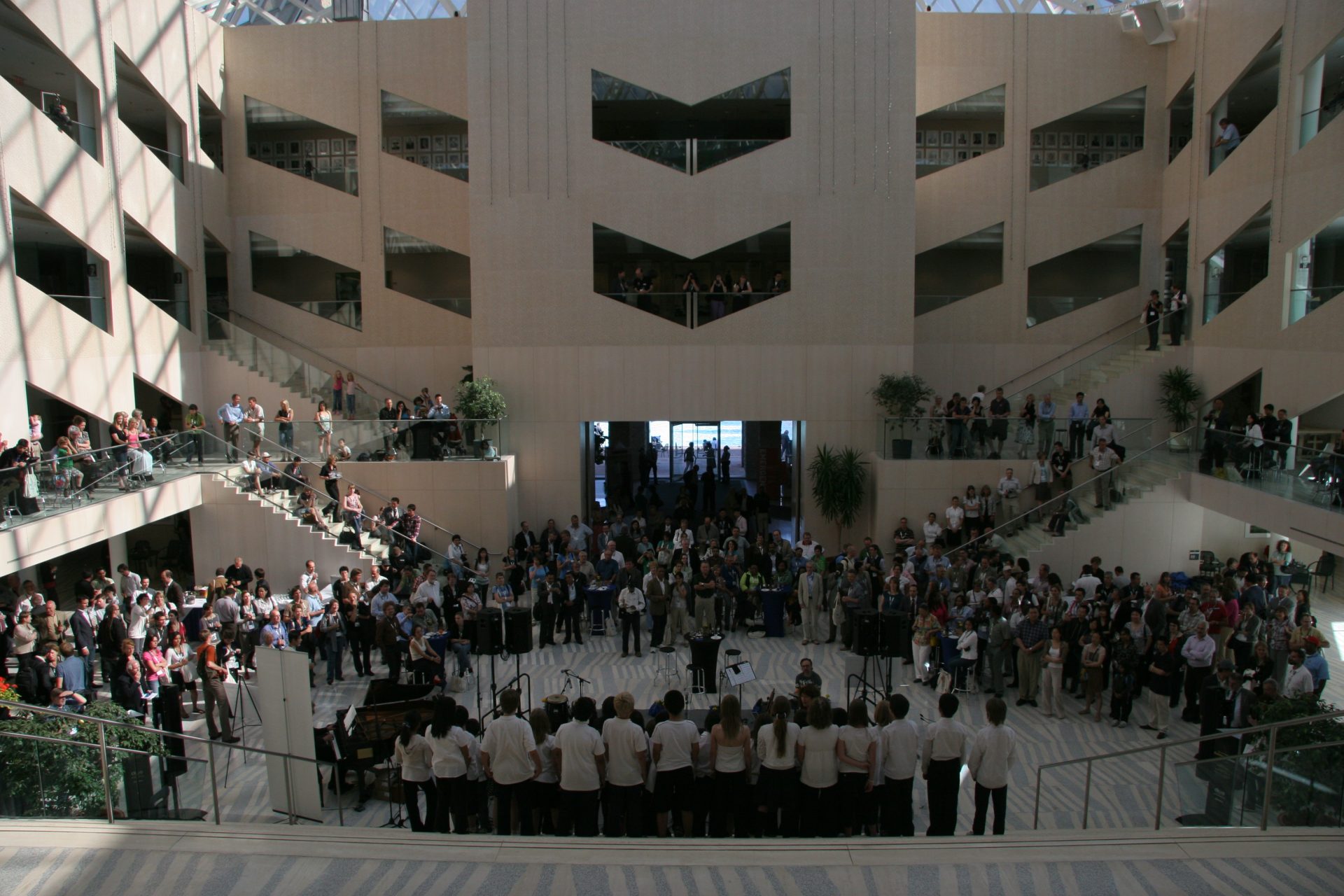 A group of guests at the ICLEI World Congress watching a group of singers performing in an atrium.